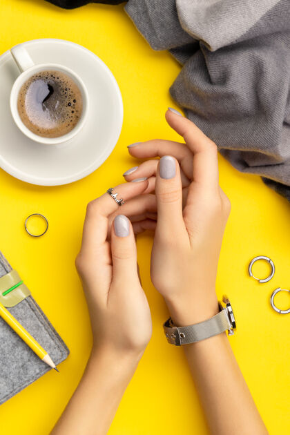 时尚女人的手和最小的指甲黄配件指甲油早餐