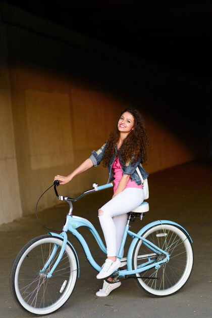 年轻城市里一个骑自行车的漂亮性感女孩的画像城市时尚时尚