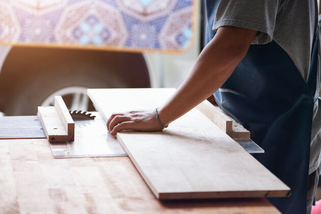 灰尘木工操作人员正在使用板材切割机为客户组装和建造木制桌子工匠转身工人