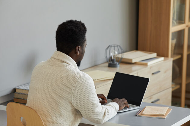 职业坐在办公室里用笔记本电脑打字的商人的后视图工作办公室上网