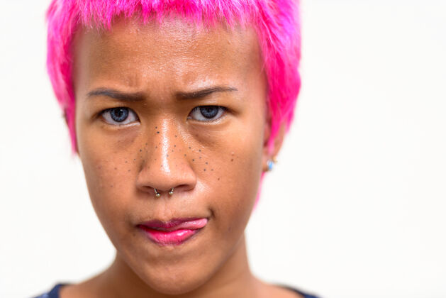 不快乐年轻叛逆的亚洲女人的肖像 粉色的头发映衬着白色的空间沮丧墙壁愤怒