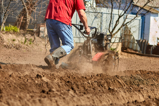 土壤园丁们用分蘖拖拉机或旋耕机 削皮机 碾磨机耕种土壤 为种植作物做好准备工作发动机庭院