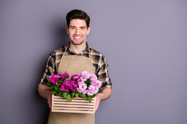 就业迷人的工人手牵手的照片惊人的粉红色花朵生长在花盆建议购买鲜花不削减穿围裙格子衬衫孤立的灰色墙壁展示工作牡丹