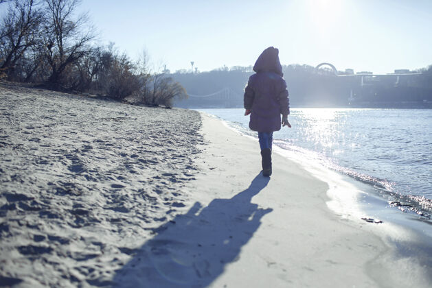 思想孩子们沿着河岸散步 享受冬日的阳光散步冬天孤独