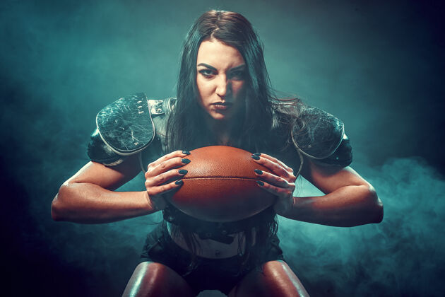 女子身穿橄榄球运动员制服的年轻黑发女郎拿着球摆姿势运动员女孩运动装