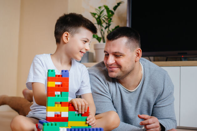 多彩一个小男孩和他的父亲一起被一个建造师扮演 建造了一座房子建造了一个家庭的家游戏童年公寓