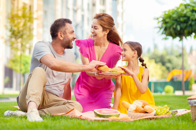 女儿家庭周末快乐的一家人坐在一起野餐休息食物野餐