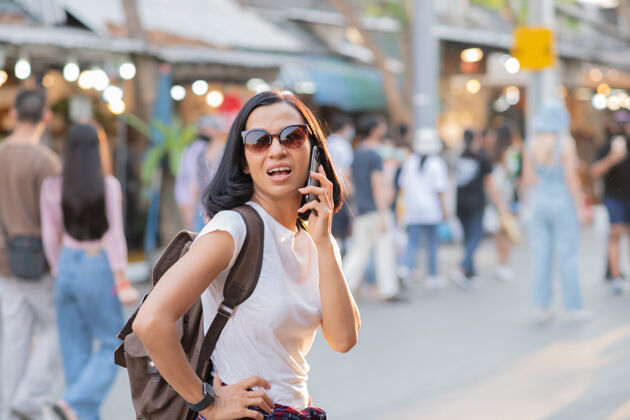 人快乐的亚洲年轻女子在街市上用手机旅游女人市场亚洲