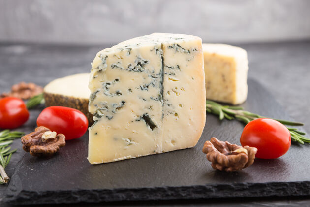 菜肴蓝色奶酪和各种类型的奶酪与迷迭香和西红柿在黑色板岩板上的黑色混凝土表面特写烹饪番茄