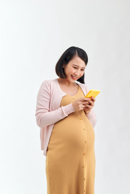 女人一个微笑可爱的孕妇肖像使用手机隔离在白色背景上怀孕怀孕韩国