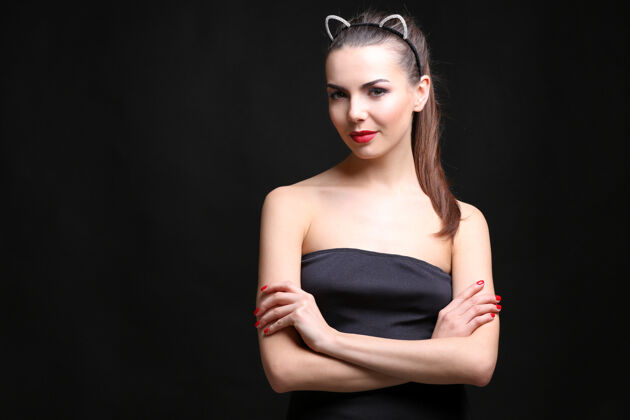 性黑墙上戴着猫耳朵的性感年轻女子肖像猫穿