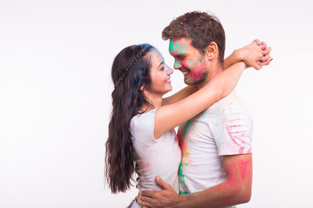 传统友谊 爱情 胡里节 人的概念-年轻夫妇在白色的胡里节上玩色彩庆祝娱乐粉