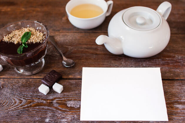 陶器木制桌子上的顶视图 配有茶具和巧克力奶油 白色空纸 自由空间食物自制勺子