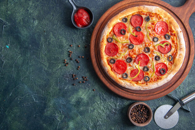 营养品木砧板上的美味比萨饼和孤立的黑暗表面上的胡椒番茄酱特写镜头午餐板比萨饼