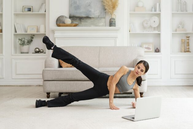 女人在家锻炼的年轻女人锻炼健康在家锻炼