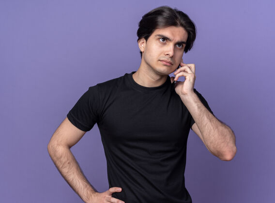 自信自信的年轻帅哥穿着黑色t恤在紫色的墙上讲电话人立场感情