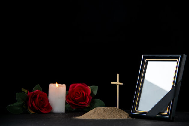 十字架小墓穴的正面图 黑色上有蜡烛和红玫瑰死亡红色玫瑰