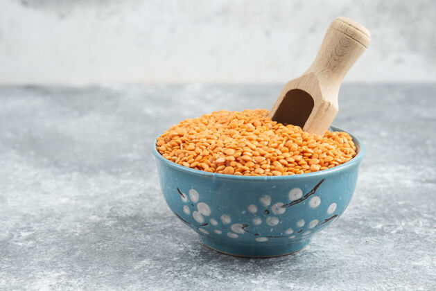 种子用勺子在大理石桌上放一碗生红豆食物干的堆