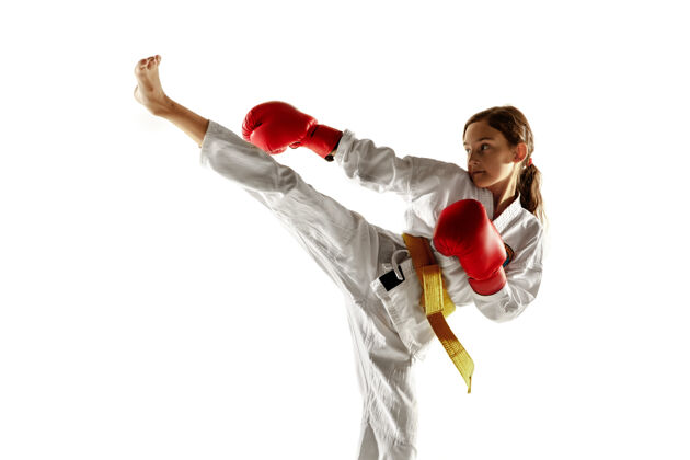 运动员自信的年轻人在和服上练习徒手格斗 武术年轻的女战士用黄腰带在白墙上训练健康的生活方式 运动 行动的概念搏击物理美丽