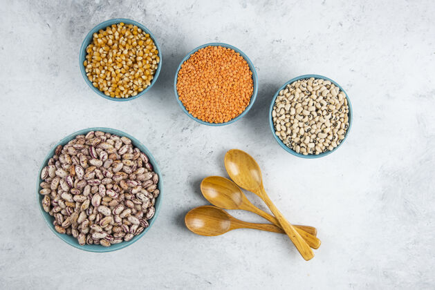 干的生的红扁豆 玉米和豆子放在蓝色的碗里 用木勺舀着仁谷物扁豆