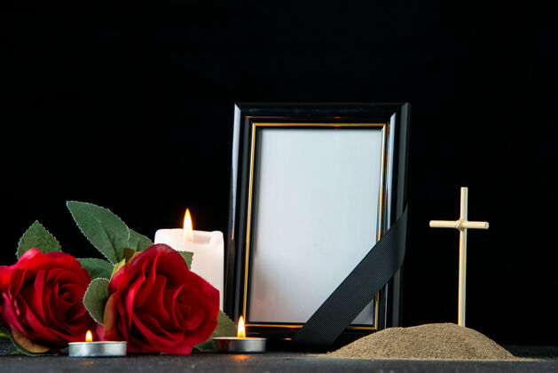 空白黑暗中 鮮花和蠟燭點綴著小墳墓的正視圖葬禮玫瑰花