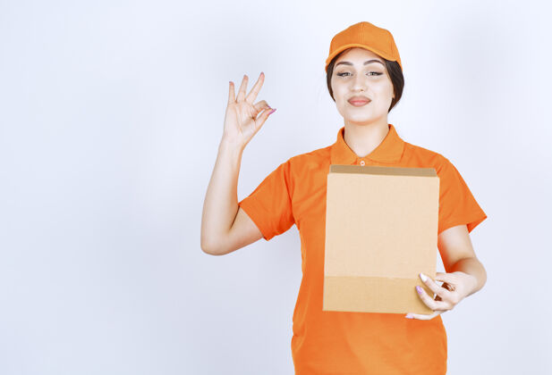 成人快乐的年轻送货员站在白墙上 手里拿着打开的箱子送货盒子纸箱