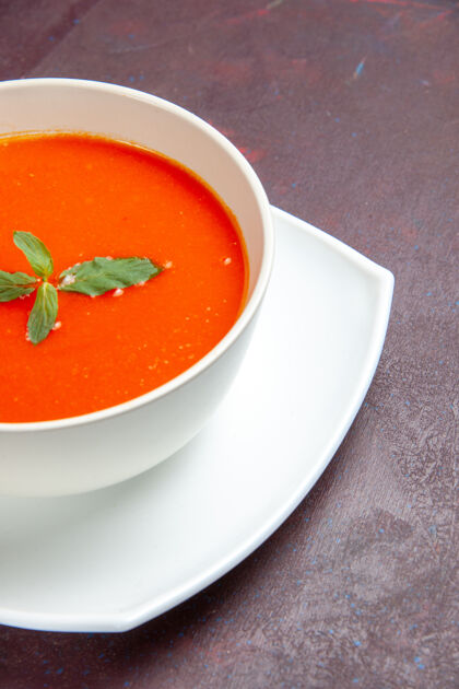 汤碗正面图美味的番茄汤美味的菜 在深色桌子上的盘子里有一片叶子 番茄色的酱汁汤叶子单饭