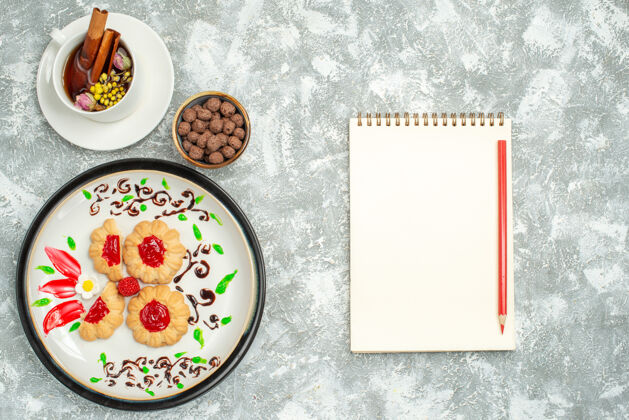 果冻俯瞰美味的饼干与红果冻和一杯茶的白色背景糖饼干蛋糕饼干甜茶茶糖化妆品