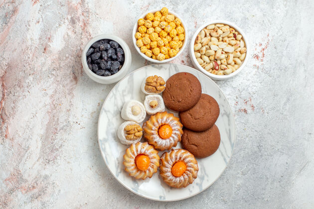 午餐俯瞰美味的饼干 白色背景上有糖果和坚果饼干甜蛋糕饼干坚果蔬菜健康饮食