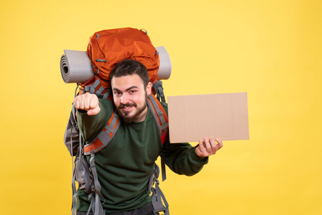 成人俯视图年轻的微笑和自信的旅行男子背着背包拿着一张没有写在黄色的床单年轻人扩音器微笑