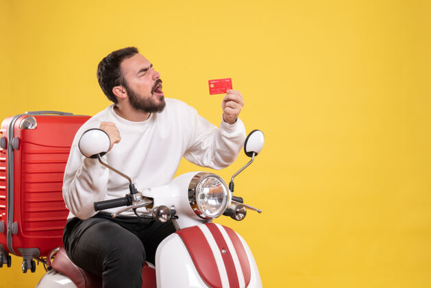 车辆旅游概念与年轻快乐和情感旅游男子坐在摩托车上 手提箱上显示黄色的银行卡年轻人高尔夫球手摩托车