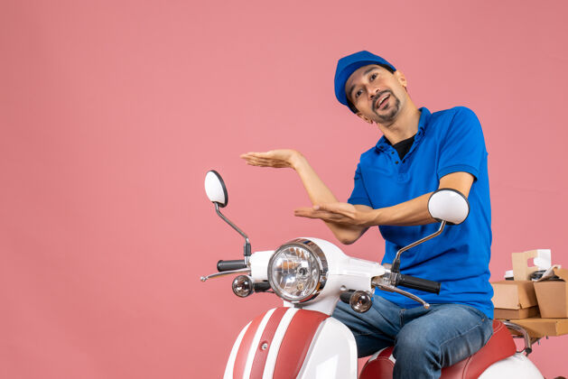 人物顶视图的快递员戴着帽子坐在滑板车上传递订单指向粉彩桃背景上的东西踏板车男摩托车