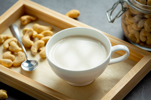 素食者纯素腰果牛奶和腰果在黑暗的背景玻璃美味牛奶灰色