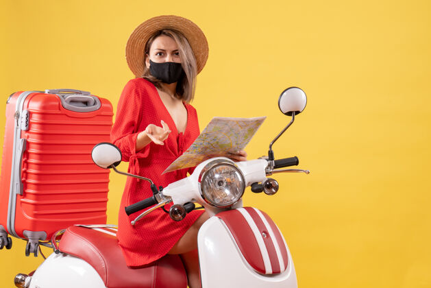摩托车拿着地图 穿着红衣服的年轻女士困惑地站在轻便摩托车上驾驶衣服红色