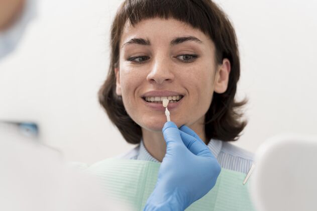牙医女病人在牙科诊所照镜子过程正畸医生乳胶手套