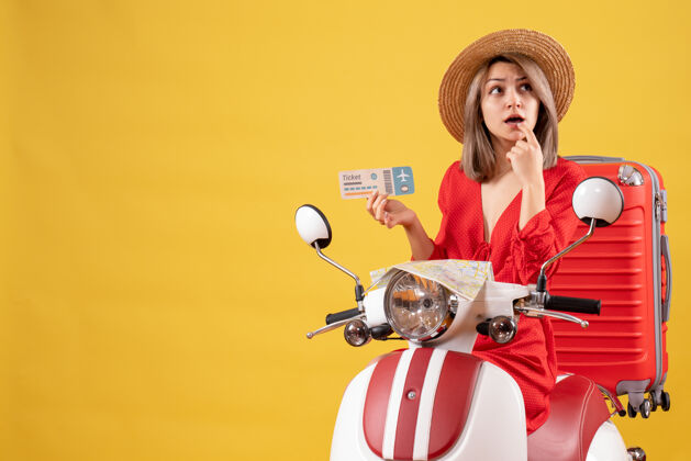 人一位体贴的年轻女士穿着红衣服 坐在轻便摩托车上拿着车票衣服红肖像