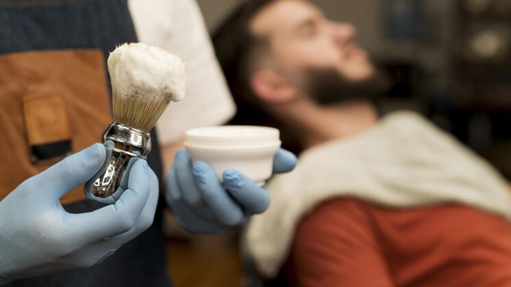 男性理发师用剃须膏勾勒男顾客的胡须轮廓理发师理发师就业