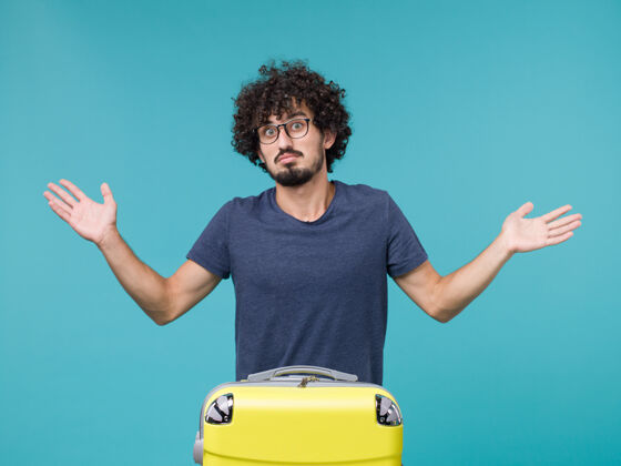手提箱带着蓝色大黄色手提箱的度假男人大假期行李