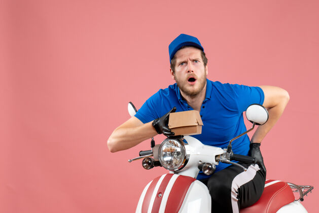 服务正面图男性信使坐在自行车上 拿着粉红色的小食品包包装工人自行车