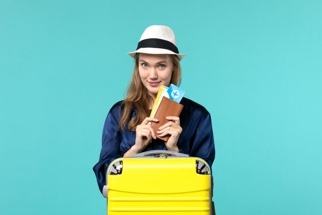 欢呼正面图年轻女子拿着机票准备在蓝色背景上度假旅行海上度假旅行飞机旅行帽子肖像旅程