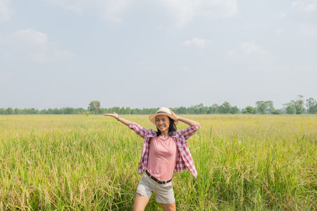 模特行走在泰国稻田里的年轻女子去清洁地球的地方旅行 发现大自然的美丽戴着帽子站着的年轻女子旅行者大米女士食物