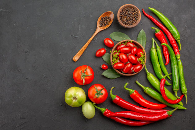 蔬菜顶视图红色和绿色的辣椒和一碗樱桃番茄黑胡椒和红色和绿色的番茄在右侧的黑色表面绿色辣椒顶部