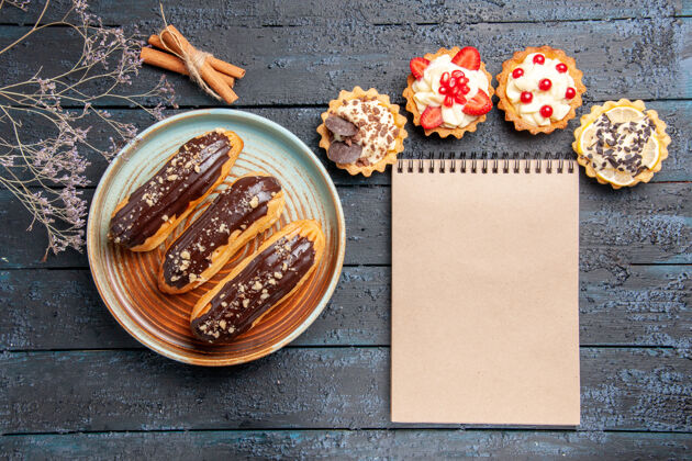 干俯瞰图：椭圆形盘子上的巧克力馅饼 肉桂干花枝和深色木桌上的笔记本食物肉桂百分比