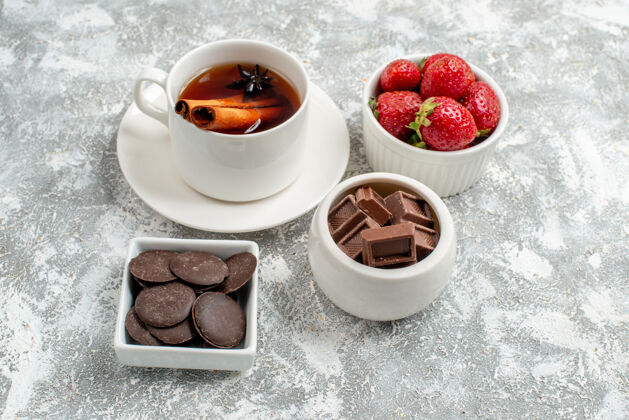杯子底部近距离观看碗与草莓和巧克力肉桂茴香种子茶在灰白色的地面盘子茶刷新