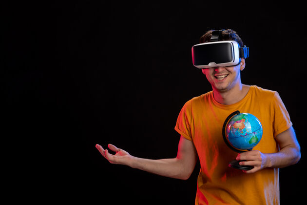 男在黑暗的表面上玩虚拟现实拿着地球仪的年轻男性年轻男性现实地球