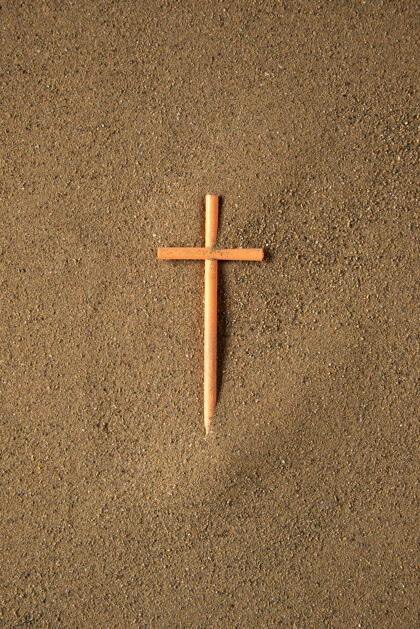 纹理把十字架贴在沙滩上葬礼沙子粗糙
