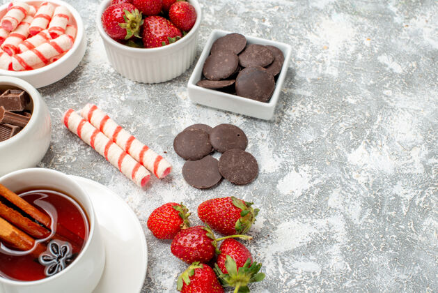 可食用水果底部近距离观察碗与草莓巧克力糖果和肉桂茴香种子茶在灰白色的背景左侧水果种子壁板