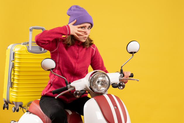 运输机正面图：戴着紫色帽子的小女孩 骑着轻便摩托车 提着手提箱轻便摩托车年轻女孩前面