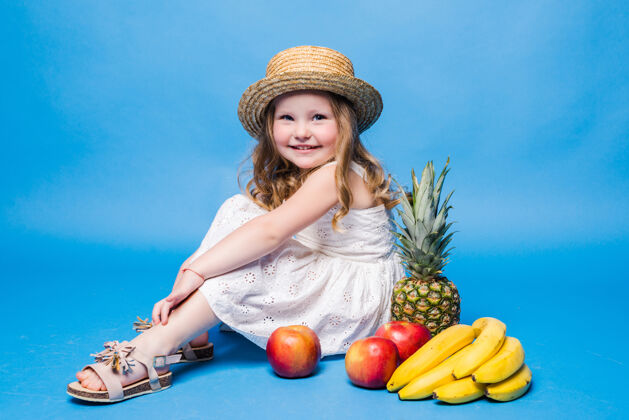可爱小女孩在蓝色的墙上玩水果食品可爱女孩