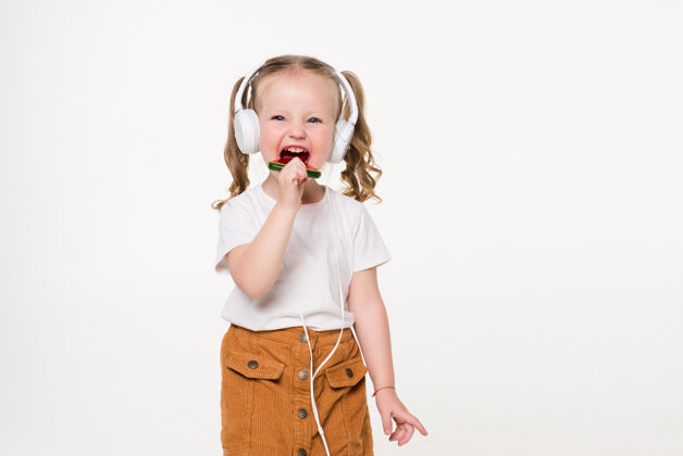 耳机美丽的小女孩用棒棒糖耳机听音乐可爱小女孩可爱